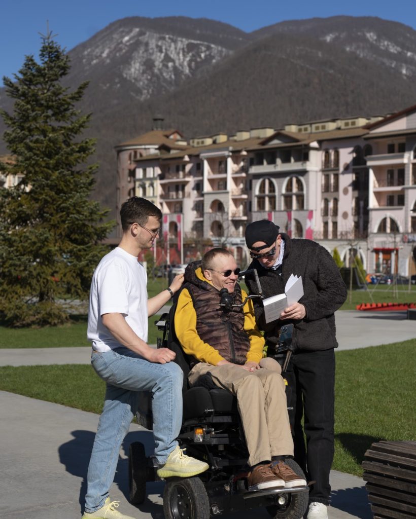 full-shot-man-helping-disabled-friend-read (Large)