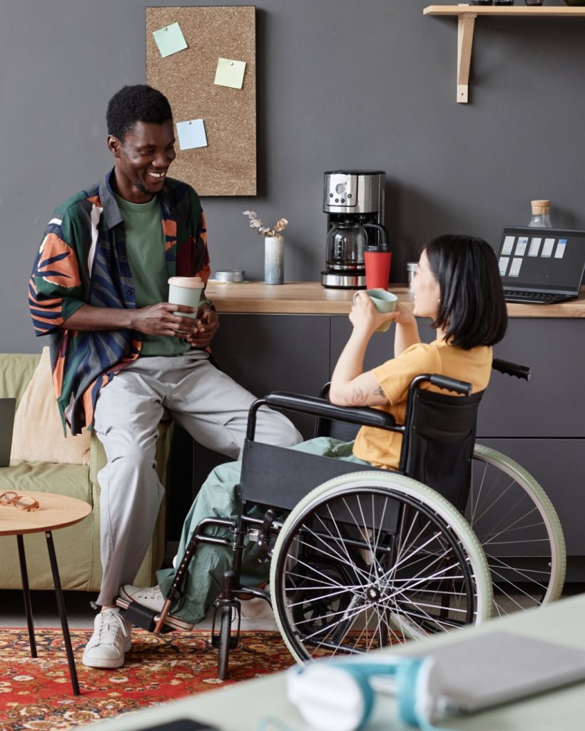 young-woman-wheelchair-enjoying-chat-with-colleague-coffee-break (Large)